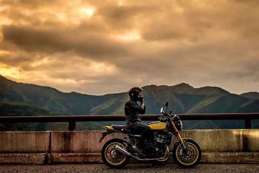 Side angle of a person seated on a parked motorcycle. opens in a new window