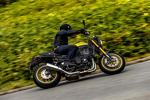 Profile angle of a person riding a motorcycle on a road. opens in a new window