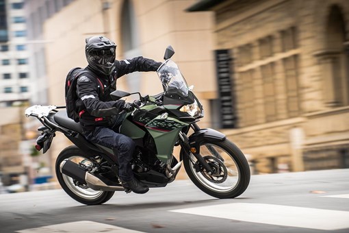 Side angle of a person riding a motorcycle on a city street. opens in a new window