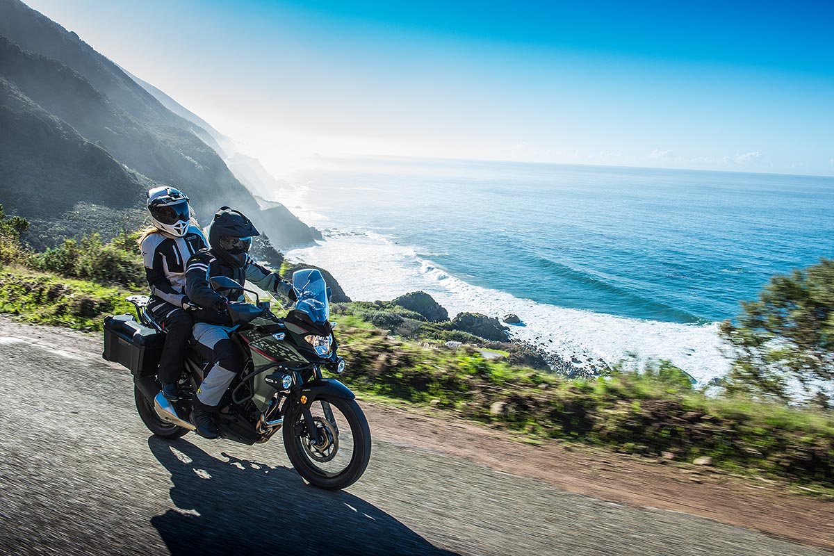 Side angle of a person and passenger riding a motorcycle on a road.