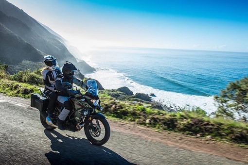 Side angle of a person and passenger riding a motorcycle on a road. opens in a new window