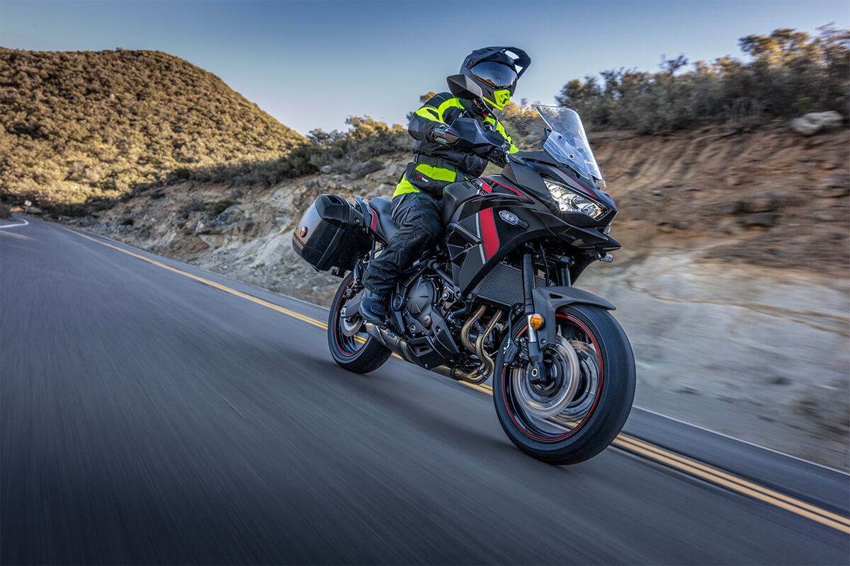 Three-quarter front angle of a person riding a black motorcycle on a street.