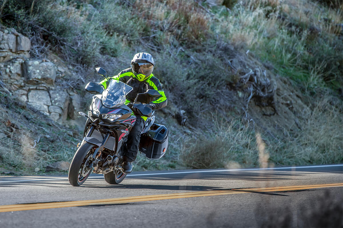 Three-quarter front angle of a person riding a black motorcycle on a road.