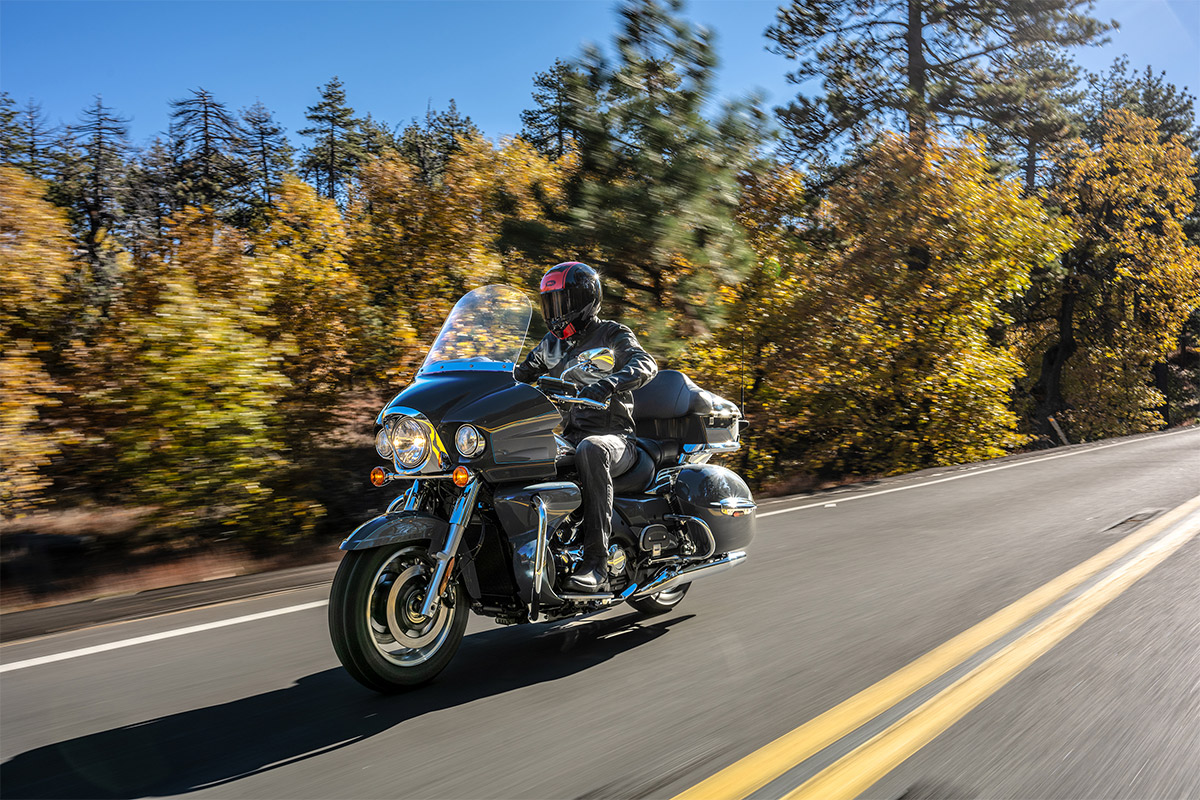 Three-quarter front angle of a person riding a black motorcycle on a road.
