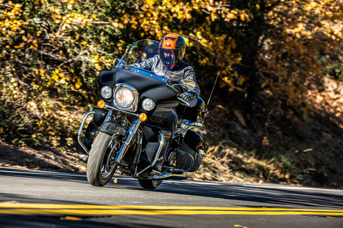 Three-quarter front angle of a person riding a motorcycle on a road.