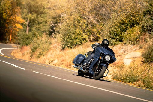 Three-quarter front angle of a person riding a motorcycle on a road. opens in a new window