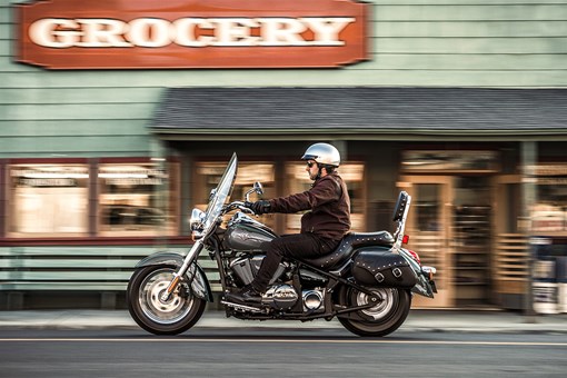 Side angle of a person riding a motorcycle on a road. opens in a new window