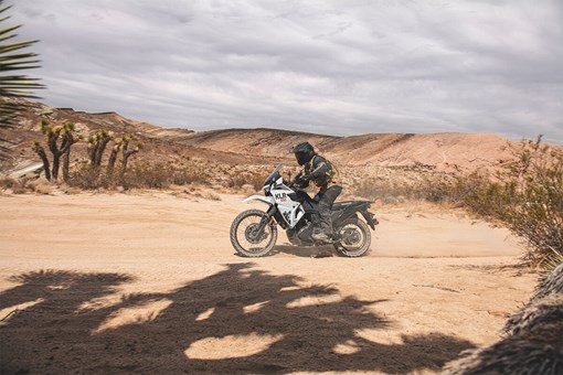 Side angle of a person on a motorcycle on a dirt trail. opens in a new window