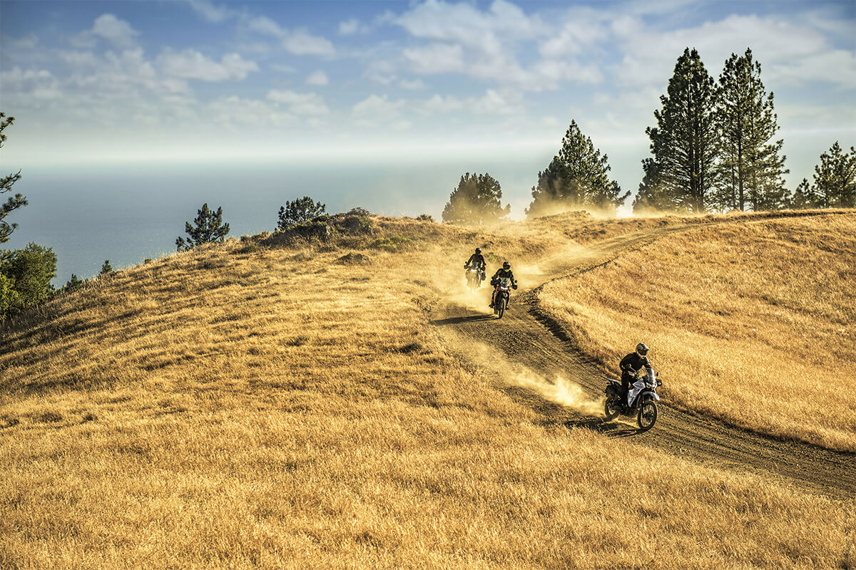Front angle of three people riding motorcycles down an off-road trail.