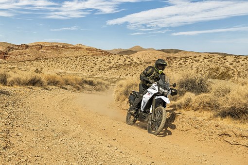 Three-quarter front angle of a person riding a motorcycle on a dirt trail. opens in a new window