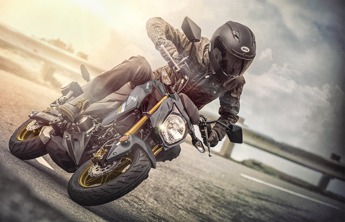 Three-quarter front angle of a person riding a motorcycle on a road.