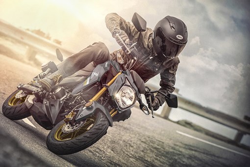 Three-quarter front angle of a person riding a motorcycle on a road. opens in a new window