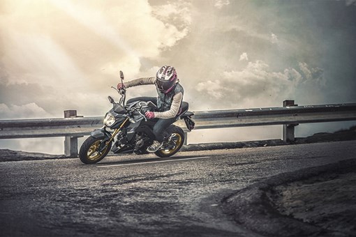 Three-quarter front angle of a person riding a motorcycle around a bend. opens in a new window