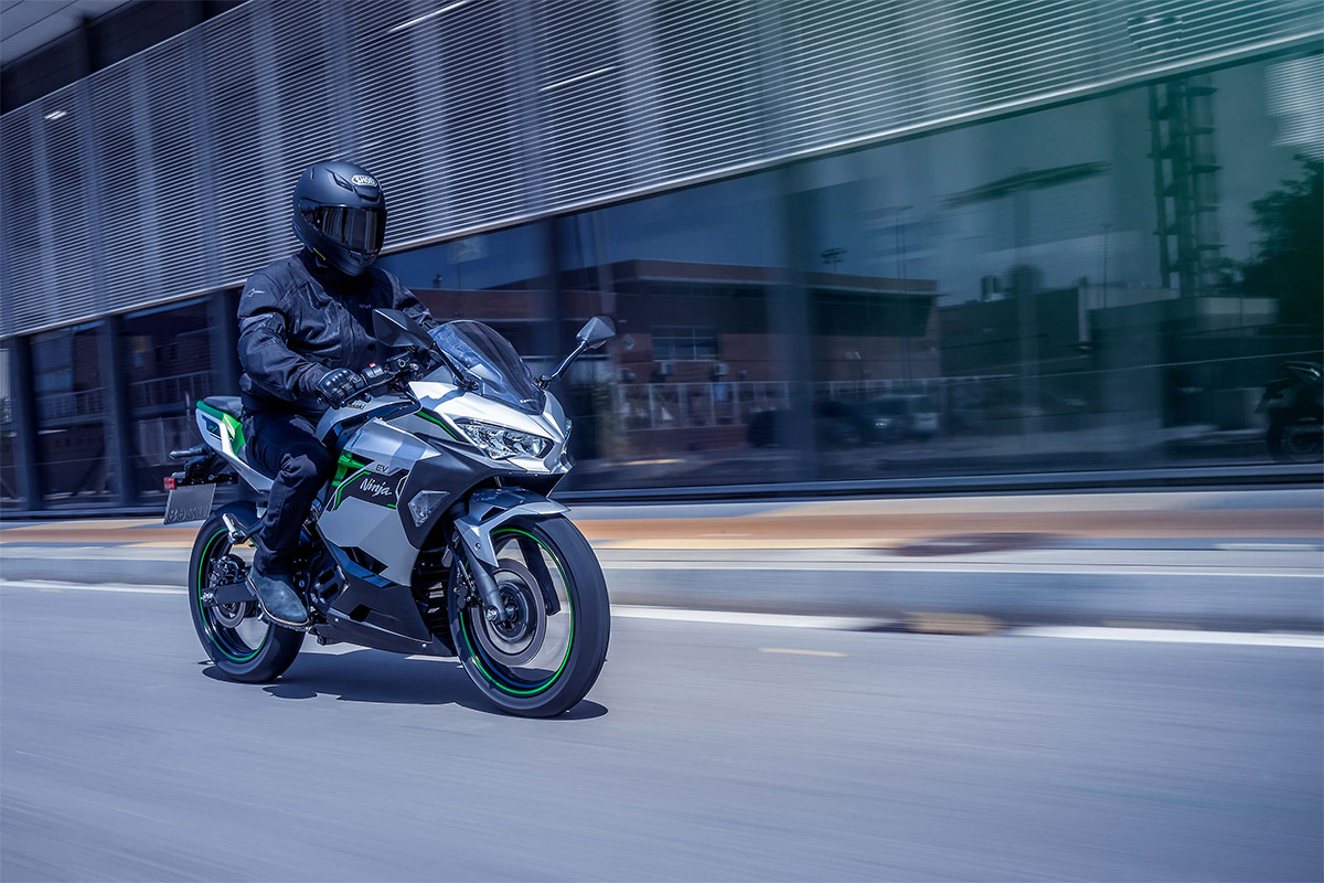 Three-quarter front angle of a person riding a motorcycle on a street.