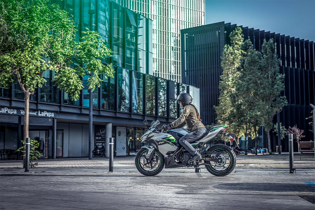 Side angle of a person riding a motorcycle in a city.