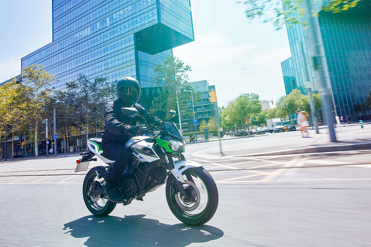 Three-quarter front angle of a person riding a motorcycle on a city street.