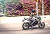 Profile angle of a person riding a green electric motorcycle on a road.