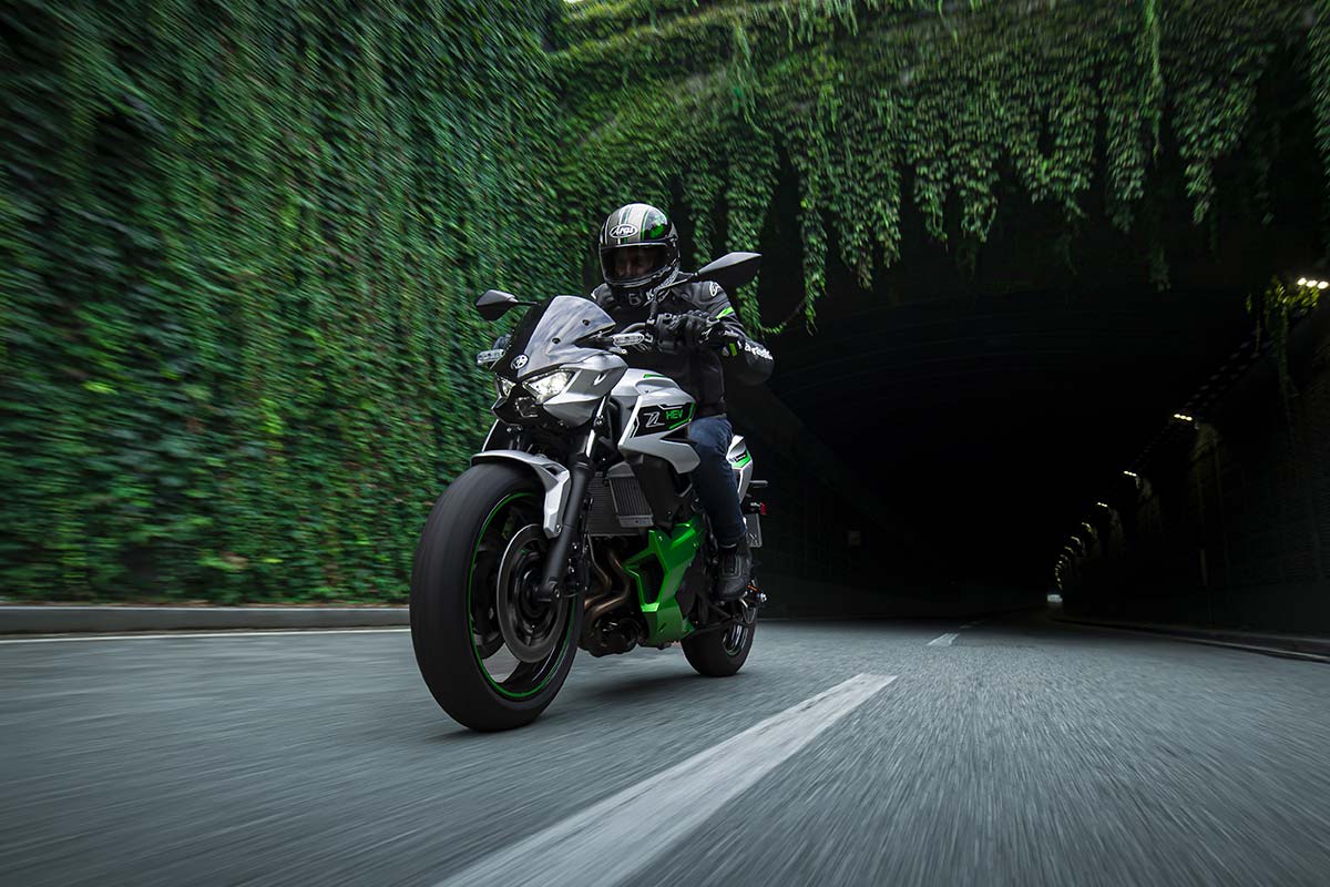 Front angle of a person riding a motorcycle out of a tunnel.