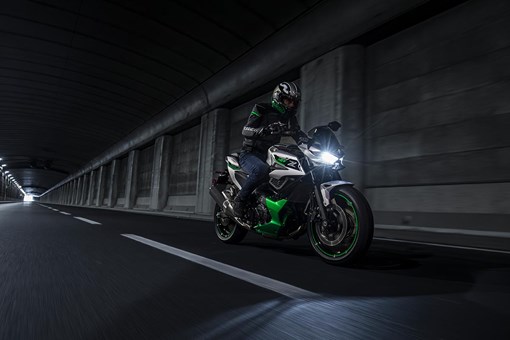 Three-quarter front angle of a person riding a motorcycle in a city at night. opens in a new window