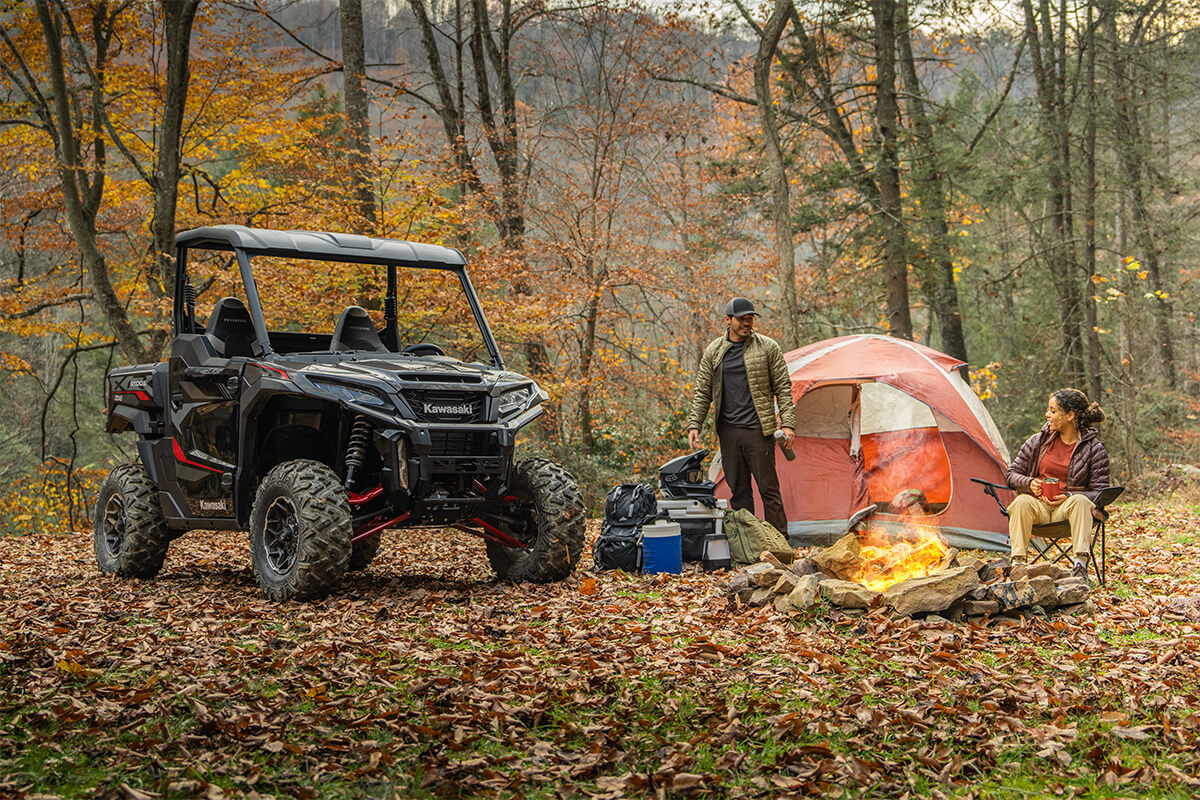 Three-quarter front angle of a side x side parked near a campsite.