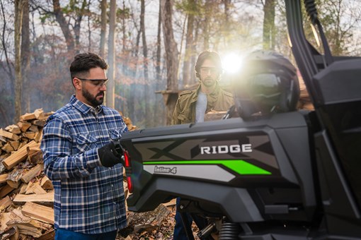 Rear angle of people loading the back of a side x side off-road. opens in a new window