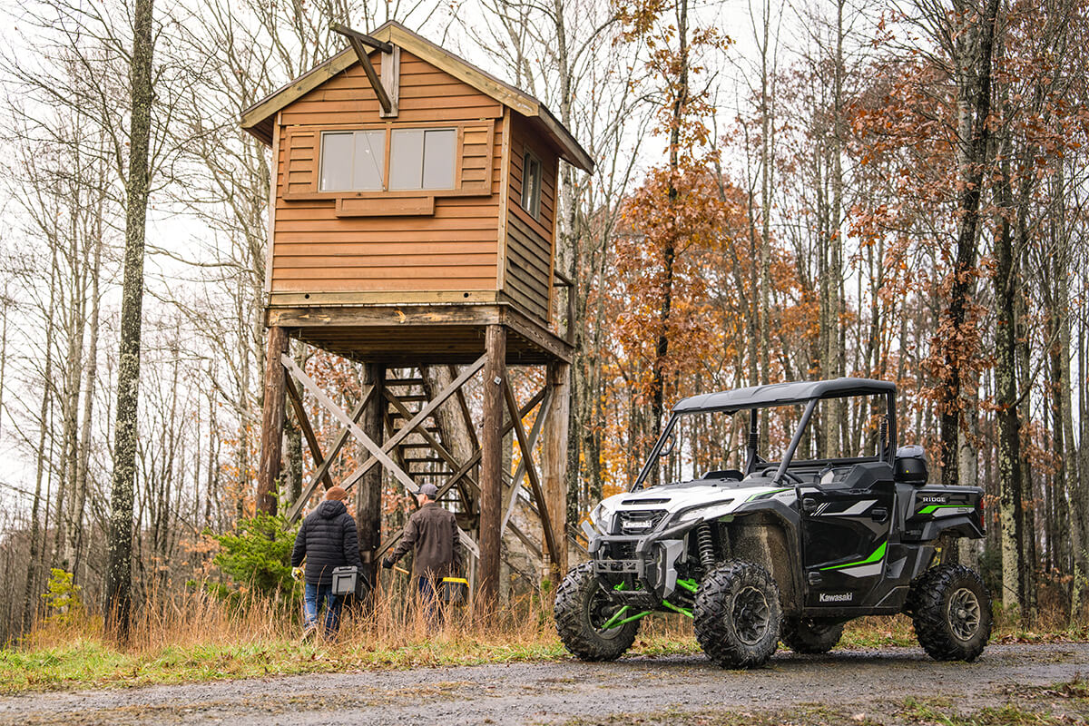 Three-quarter front angle of a side x side parked near an outpost.