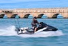 Side angle of a person riding a personal watercraft in water.