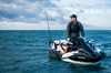 Three-quarter front angle of a person standing on a personal watercraft in the ocean.