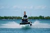 Front angle of a person riding a personal watercraft in water.