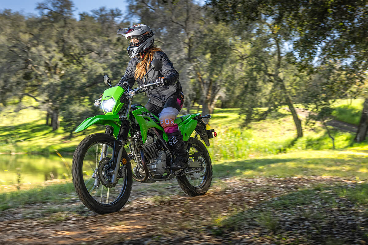 Three-quarter front angle of a person riding a motorcycle on a dirt trail.