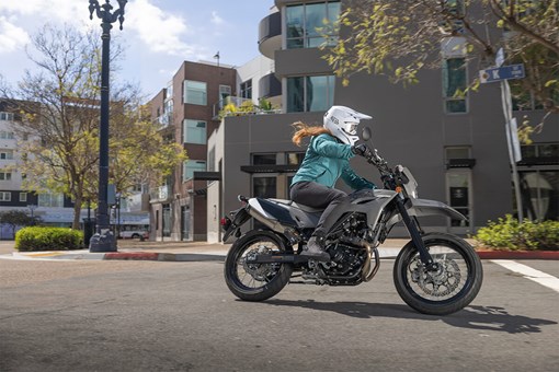 Side angle of a person riding a motorcycle on a city street. opens in a new window