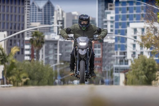 Front angle of a person riding a motorcycle on a city street. opens in a new window