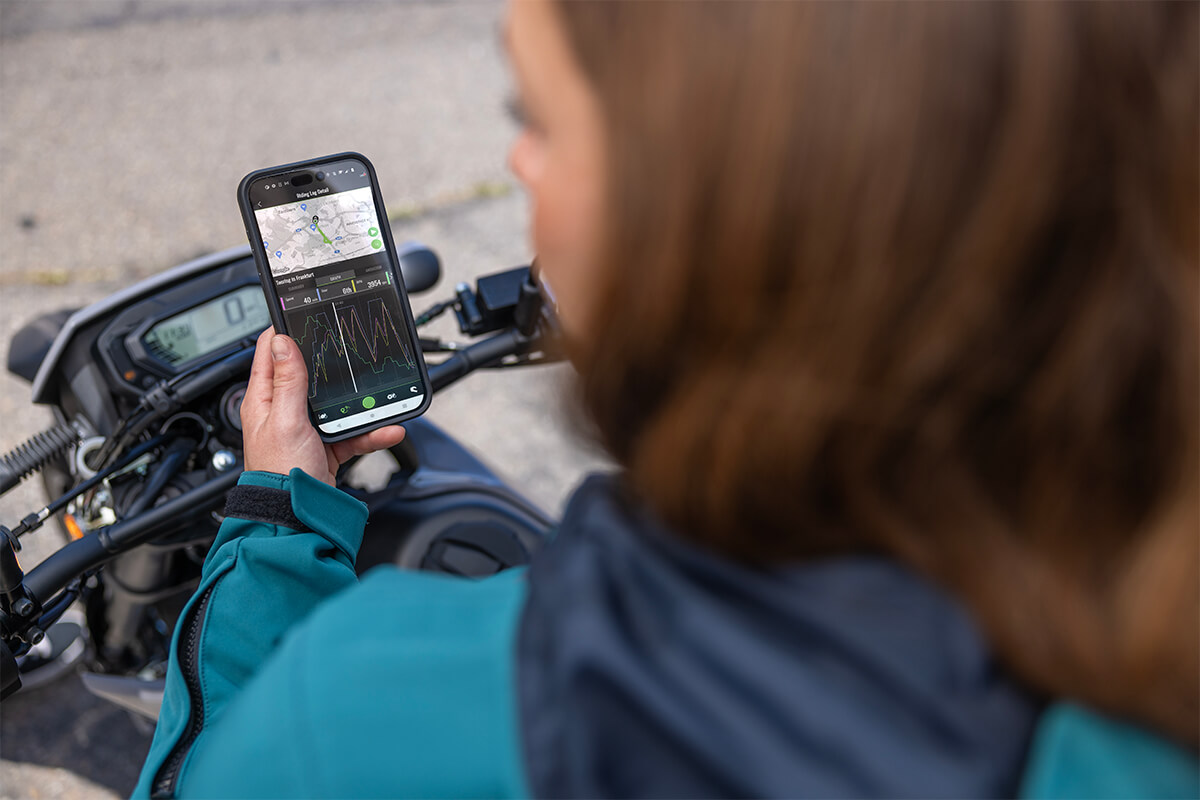 Over the shoulder angle of a person looking at their phone while sitting on a parked motorcycle.