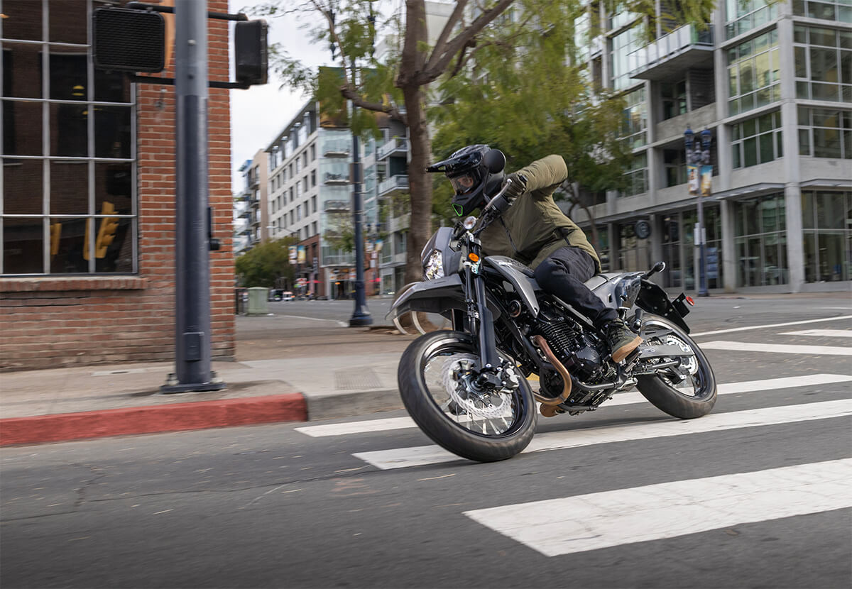 Three-quarter front angle of a person making a turn on a motorcycle in an urban city.