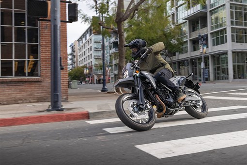 Three-quarter front angle of a person making a turn on a motorcycle in an urban city. opens in a new window