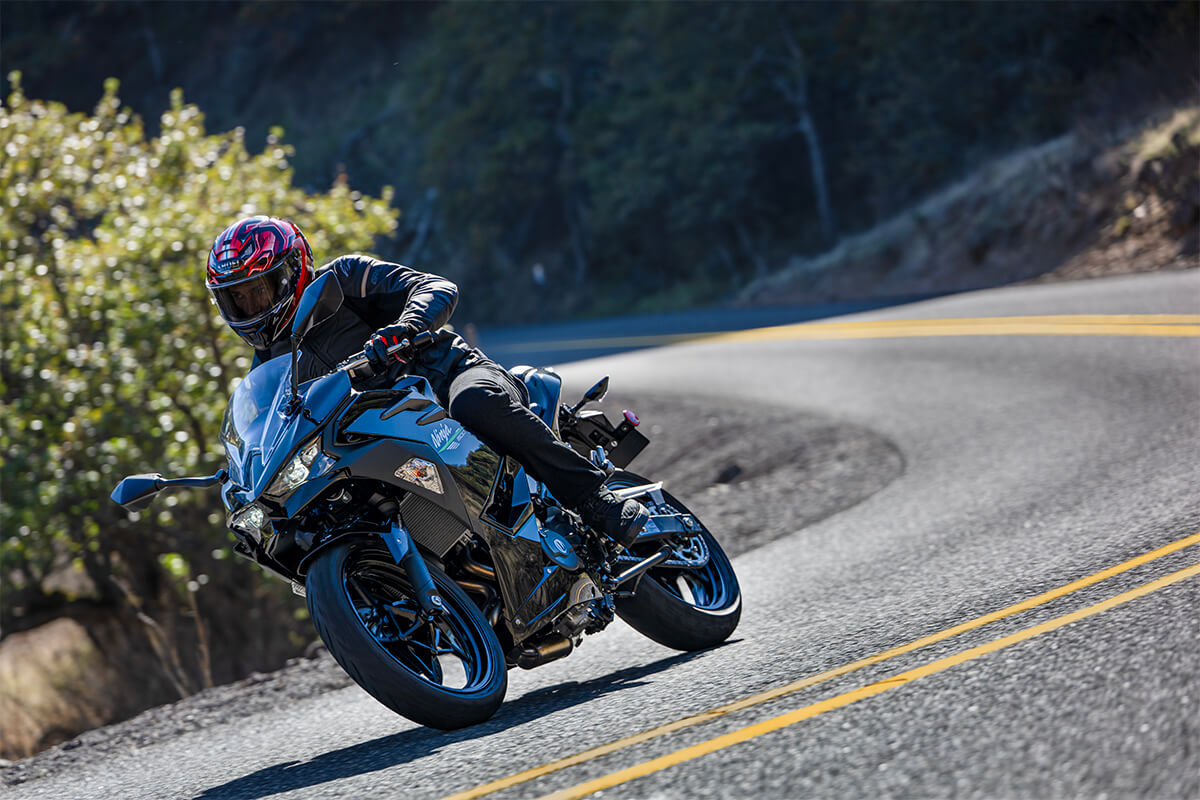 Three-quarter front angle of a person riding a motorcycle around a bend.