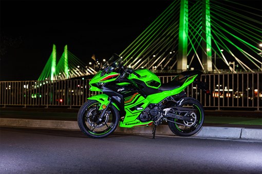Side angle of a motorcycle parked in front of a bridge. opens in a new window