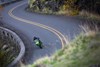 Front angle of a person riding a motorcycle on a winding road.
