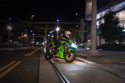 Three-quarter front angle of a person riding a motorcycle on a city street. opens in a new window