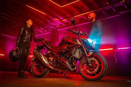 Profile angle of a motorcycle parked in a garage near people. opens in a new window