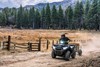 Three-quarter front angle of a person riding an ATV on a ranch.