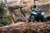 Front angle of a person riding an ATV on rocky terrain.