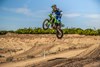 Three-quarter front angle of a person making a jump on a motorcycle off-road.