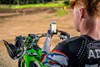 Over-the-shoulder POV of a person using a smartphone while standing near a parked motorcycle.