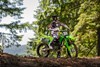 Side angle of a person seated on a motorcycle on a dirt track.