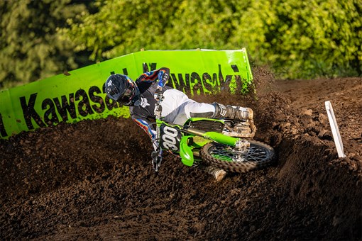 Three-quarter front angle of a person riding a green motorcycle through a turn. opens in a new window