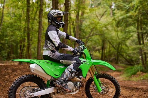 Side angle of a person standing next to a parked motorcycle off-road. opens in a new window