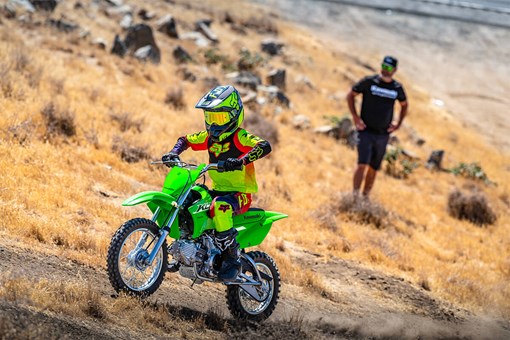 Three-quarter front angle of a person riding a motorcycle up an off-road hill. opens in a new window