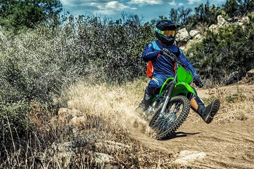 Three-quarter front angle of a person coming out of a turn on a motorcycle off-road. opens in a new window
