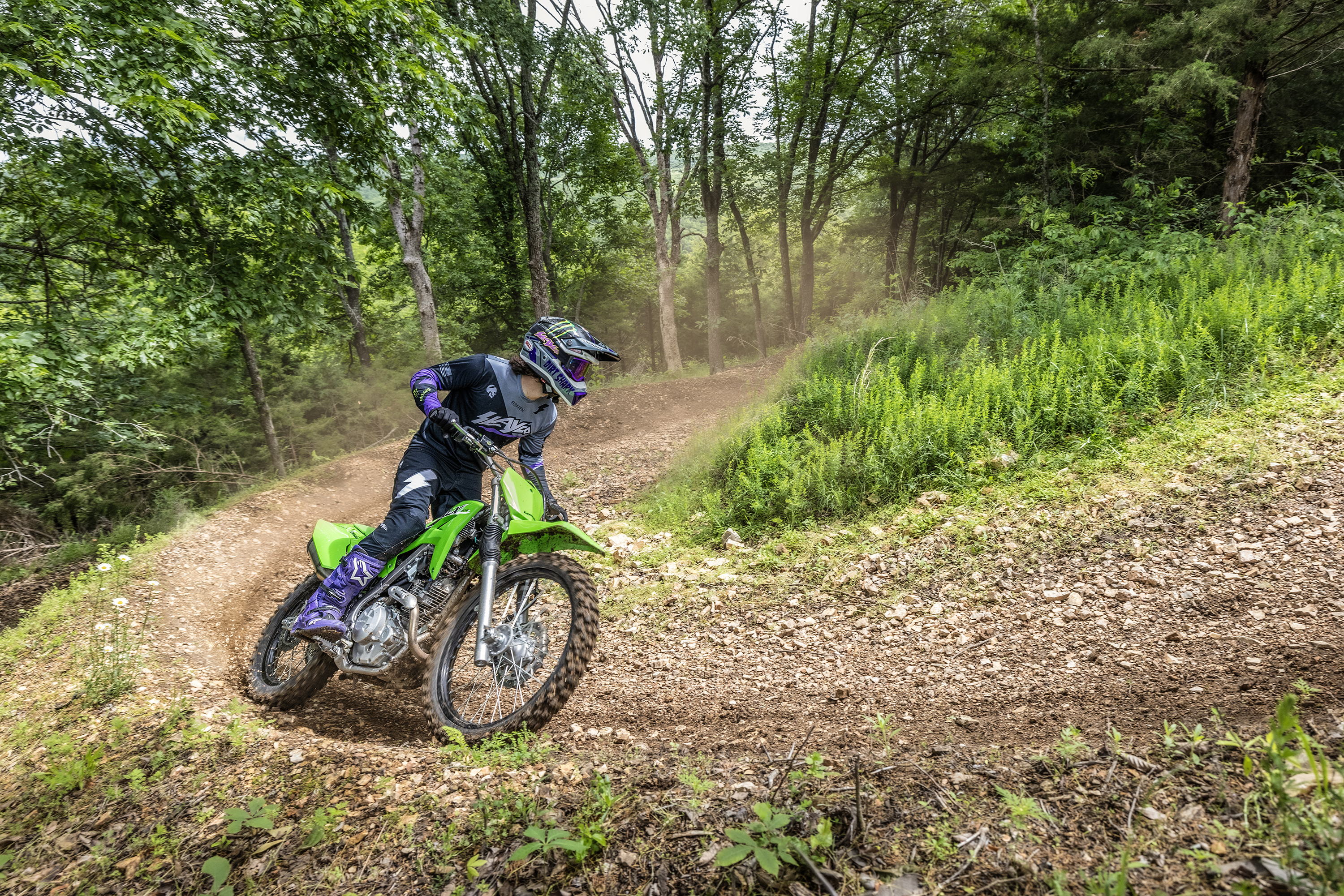 Three-quarter front angle of a person leaning into a turn on a motorcycle off-road.